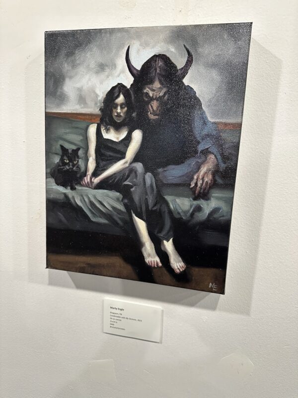 Comfortable with My Demons displayed on a white wall beside an artwork label